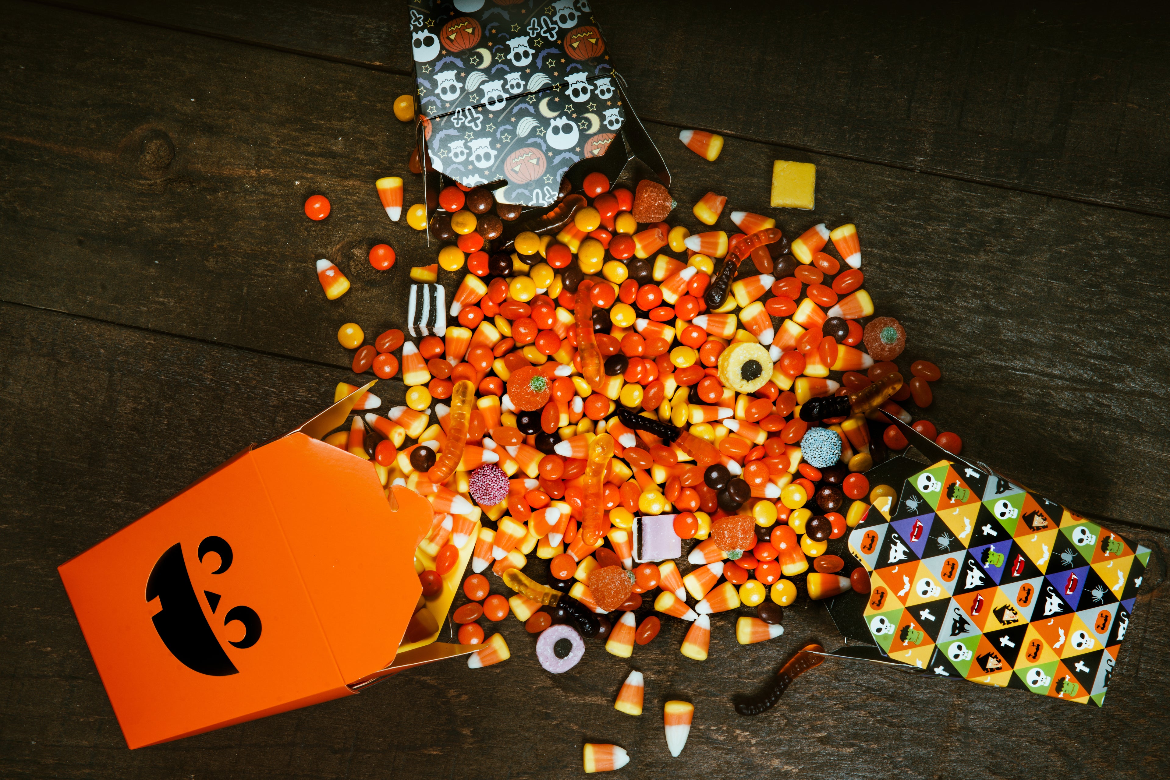 Vibrant Halloween candy assortment, featuring candy corn and assorted sweets, elegantly presented in our Halloween gift baskets on a rustic wooden floor
